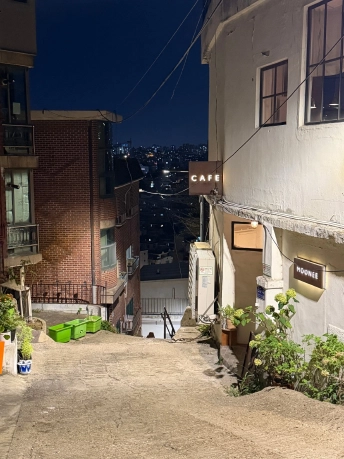 坂道の途中にあるCAFEとMOONEEの看板と、その下に広がる夜の住宅街