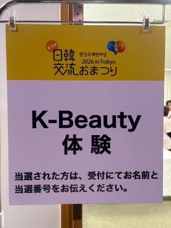 「K-Beauty体験」と書かれ、当選者に受付で名前と当選番号を伝えるよう案内する看板